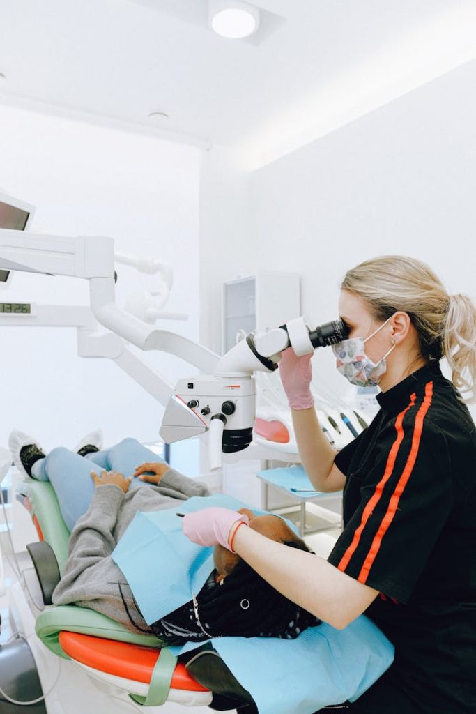 dental-clinic-3845748 Dentist using a microscope for precision during a dental procedure in a clinic.